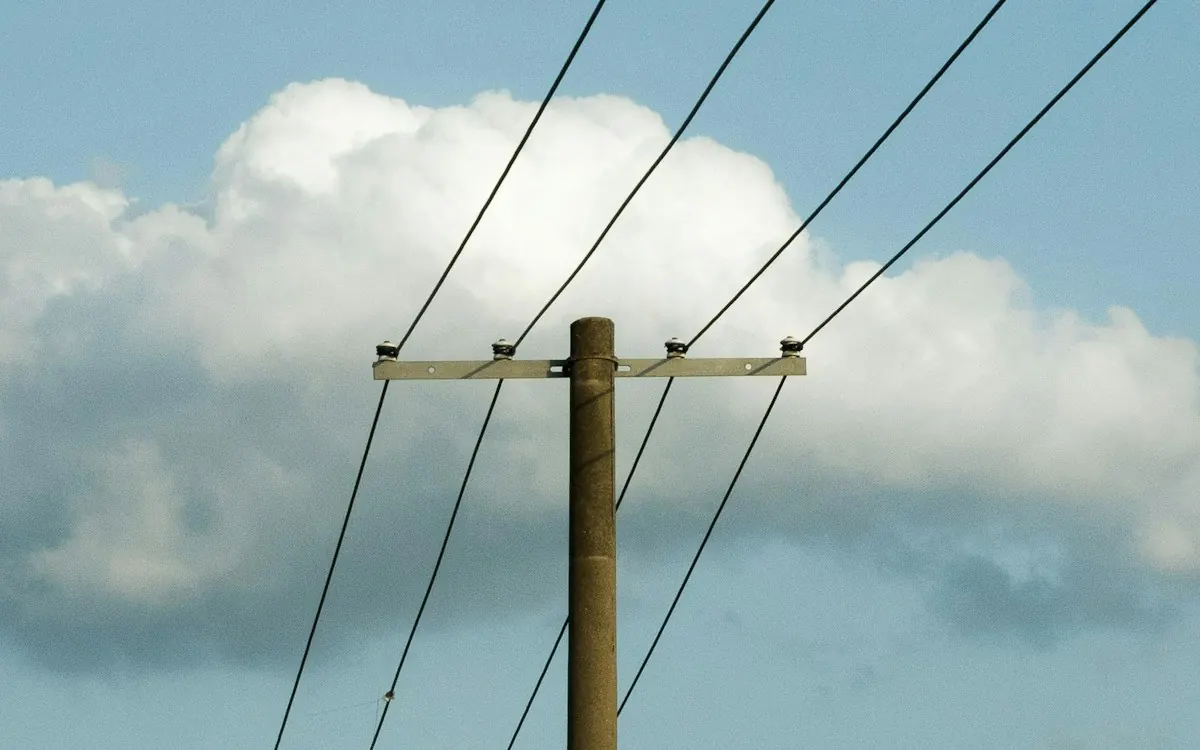 Wooden telephone pole carrying overhead lines against a cloudy sky