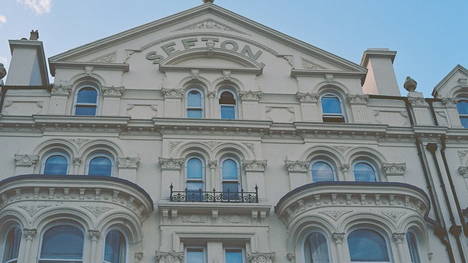The ornate white facade of the Sefton building on Douglas promenade, Isle of Man, against a blue sky